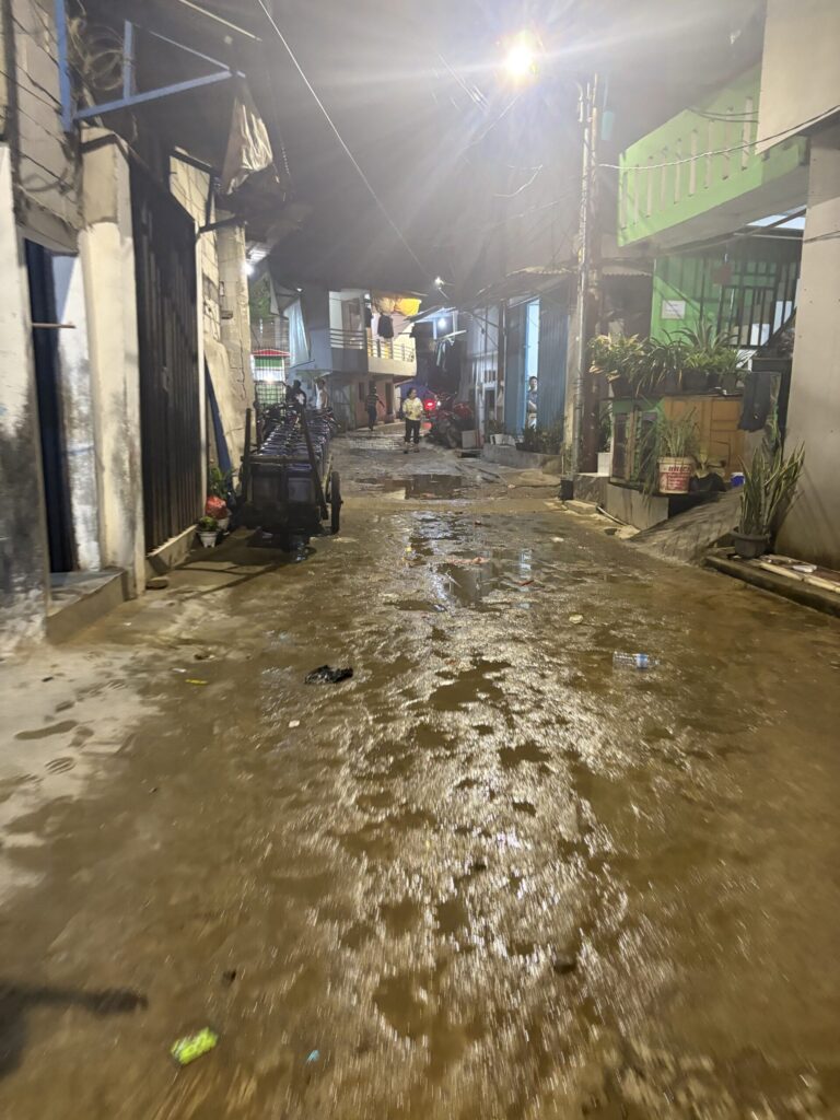 Image of a damp street in North Jakarta. Relatively low amount of litter visible